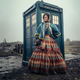 A woman in a bonnet, a colonial blue jacket, and a long red dress stands in front of the TARDIS.